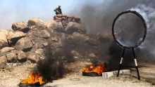 A Turkish-backed Syrian fighter is seen behind smoking tires